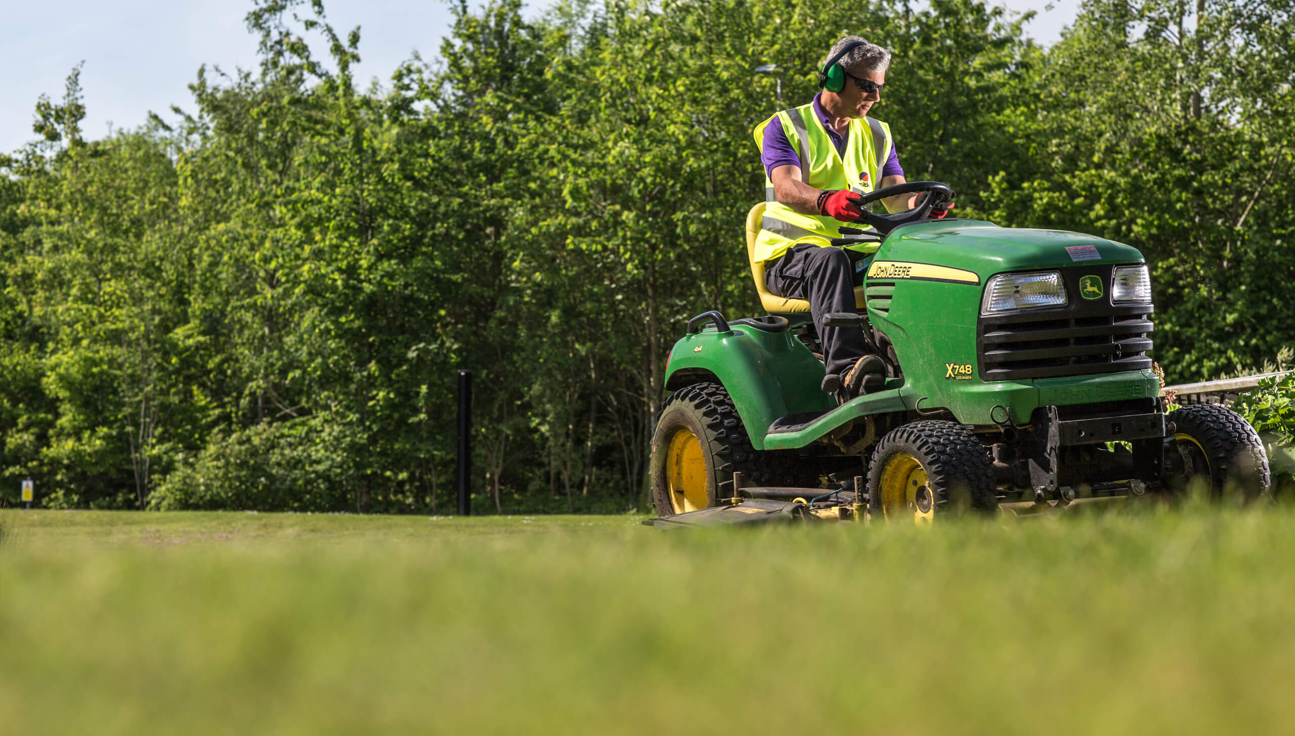 Mitie Landscaping employee on a ride-on mower