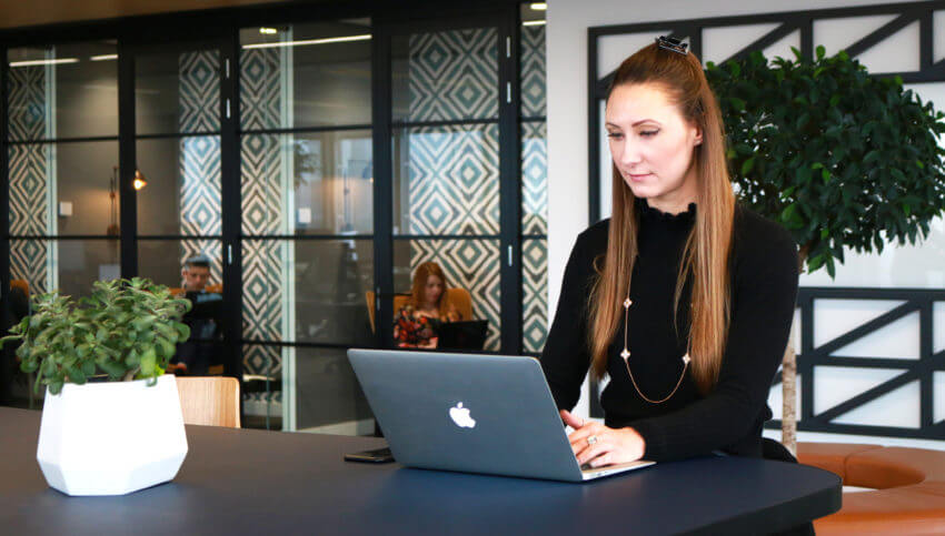 Woman using a laptop in an office, with quiet spaces in the background