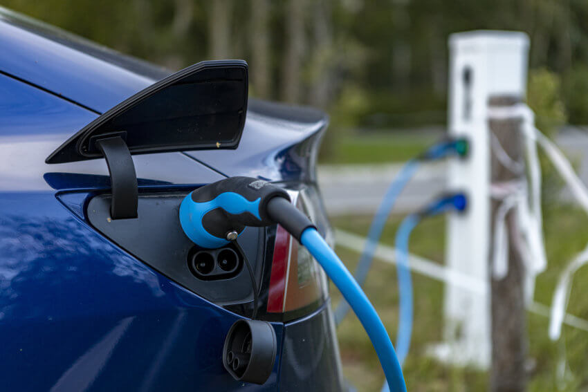 Close-up of a blue electric vehicle being plugged in to charge