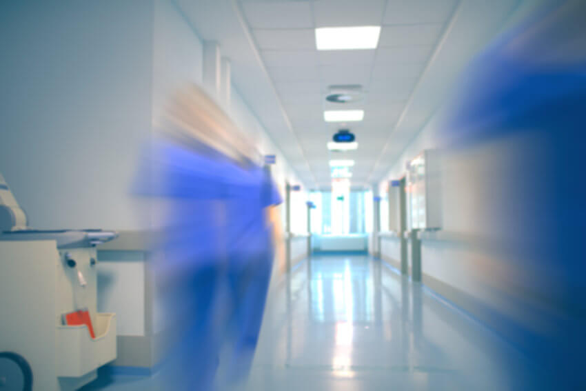 Blurred health workers walking down a hospital corridor
