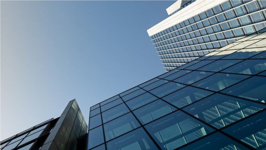 Outside of glass office building, looking up at the side and a blue sky