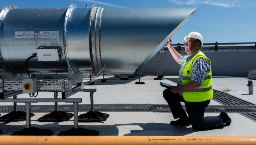 Mitie engineer in safety gear inspecting a roof vent