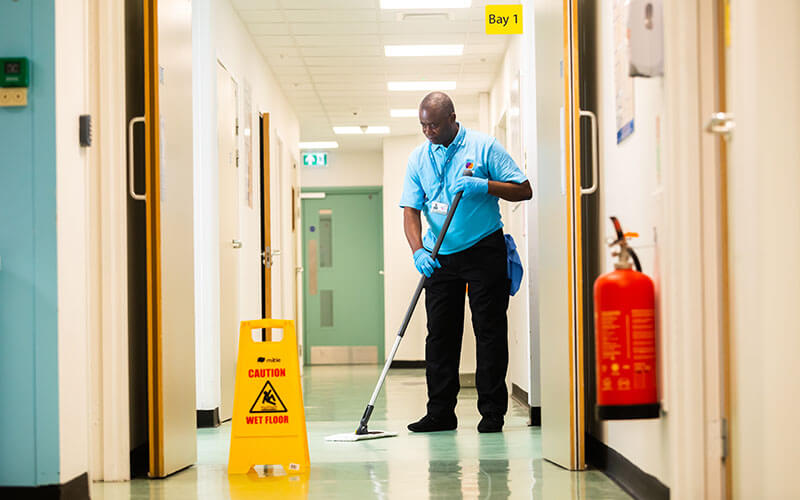 Mitie hospital cleaner mopping the floor in a corridor