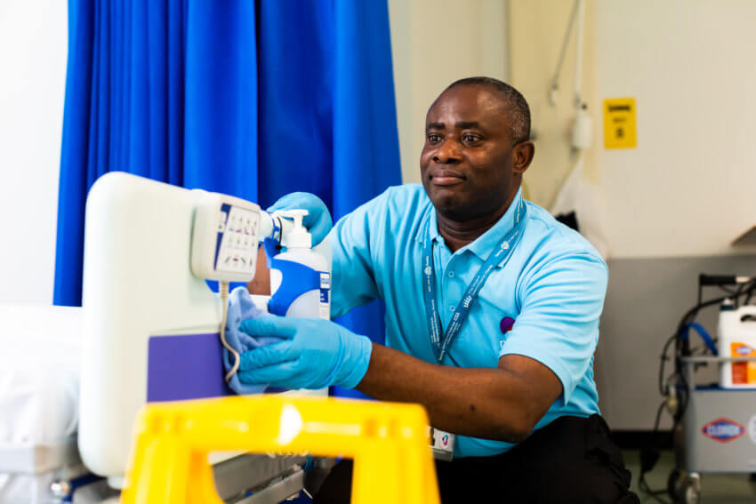 Mitie employee cleaning a white hospital bed frame