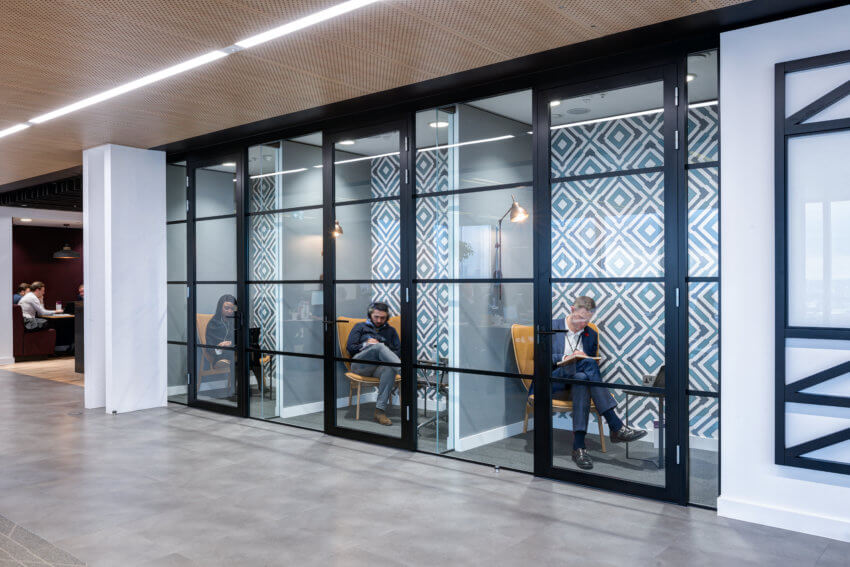 Three soundproof rooms with glass frontage, with three employees taking video calls inside them