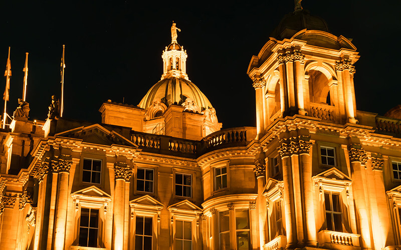 A close-up of The Mound building in Edinburgh, lit up yellow at night