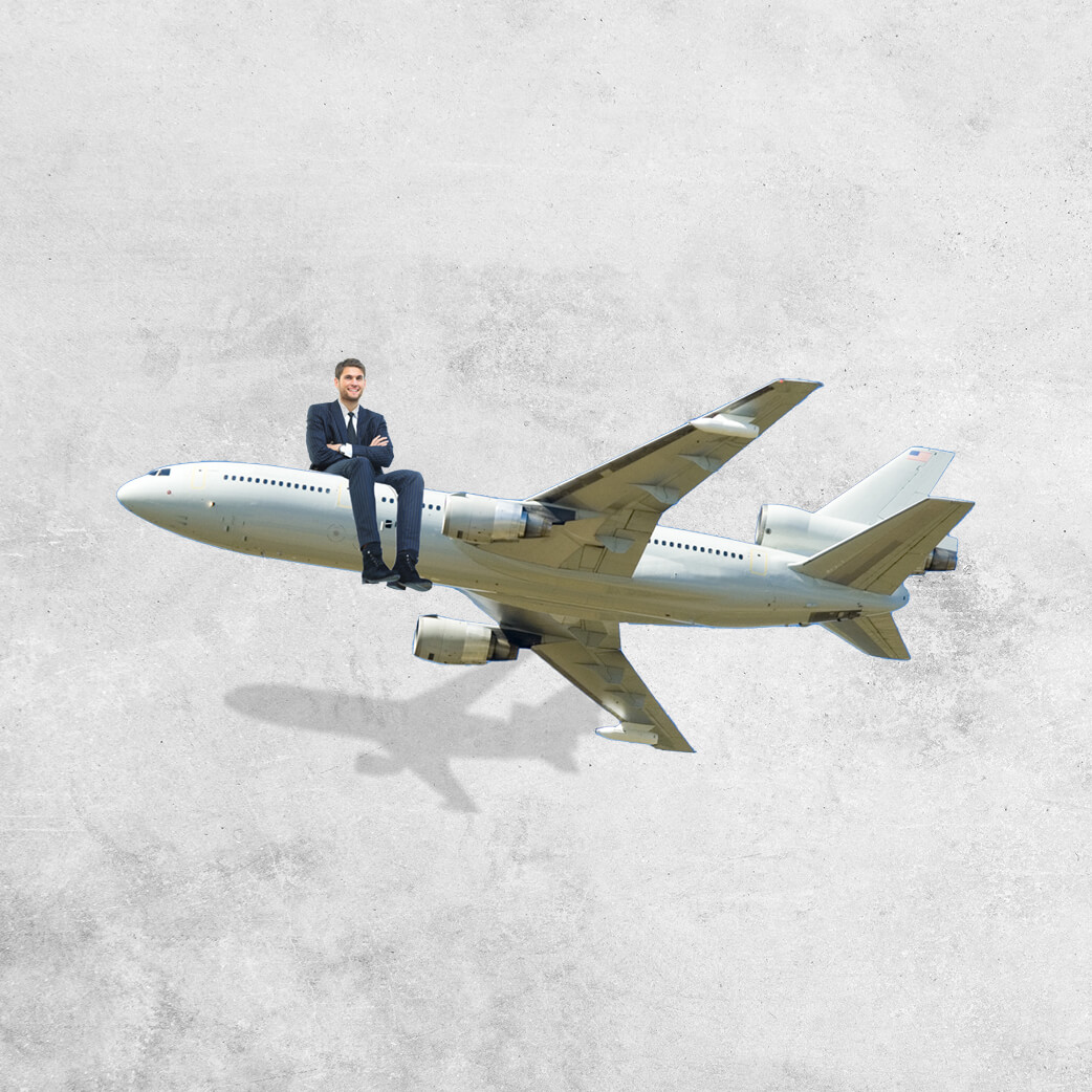 Man in a suit sitting on the nose of a small commercial aeroplane