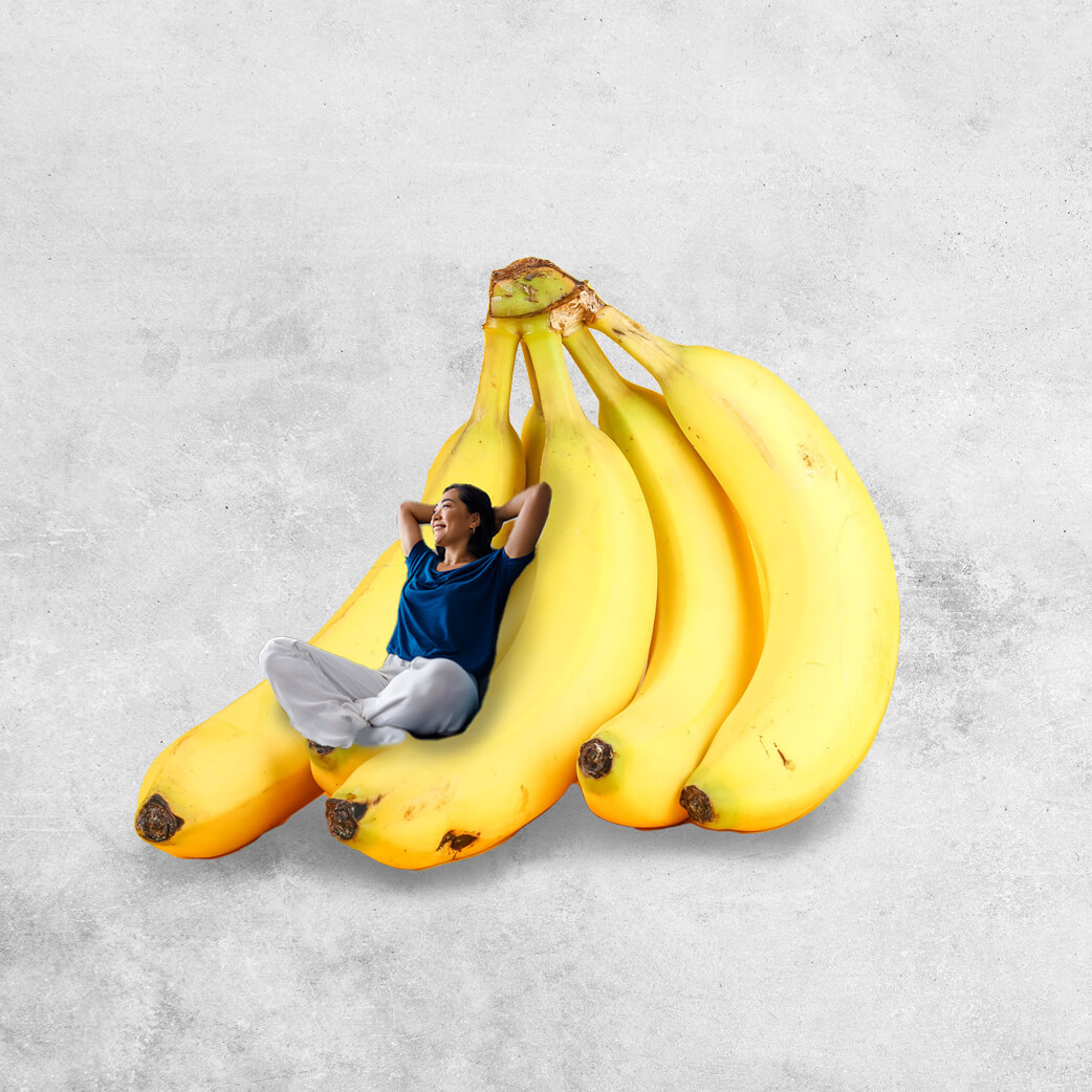 Woman lying back on an oversized bunch of yellow bananas