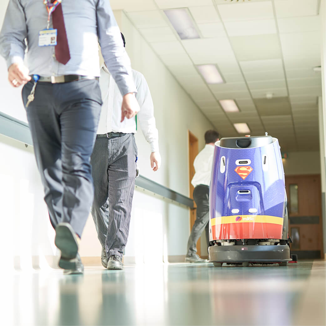 Mitie cleaning robot with a Superman design in a hospital corridor