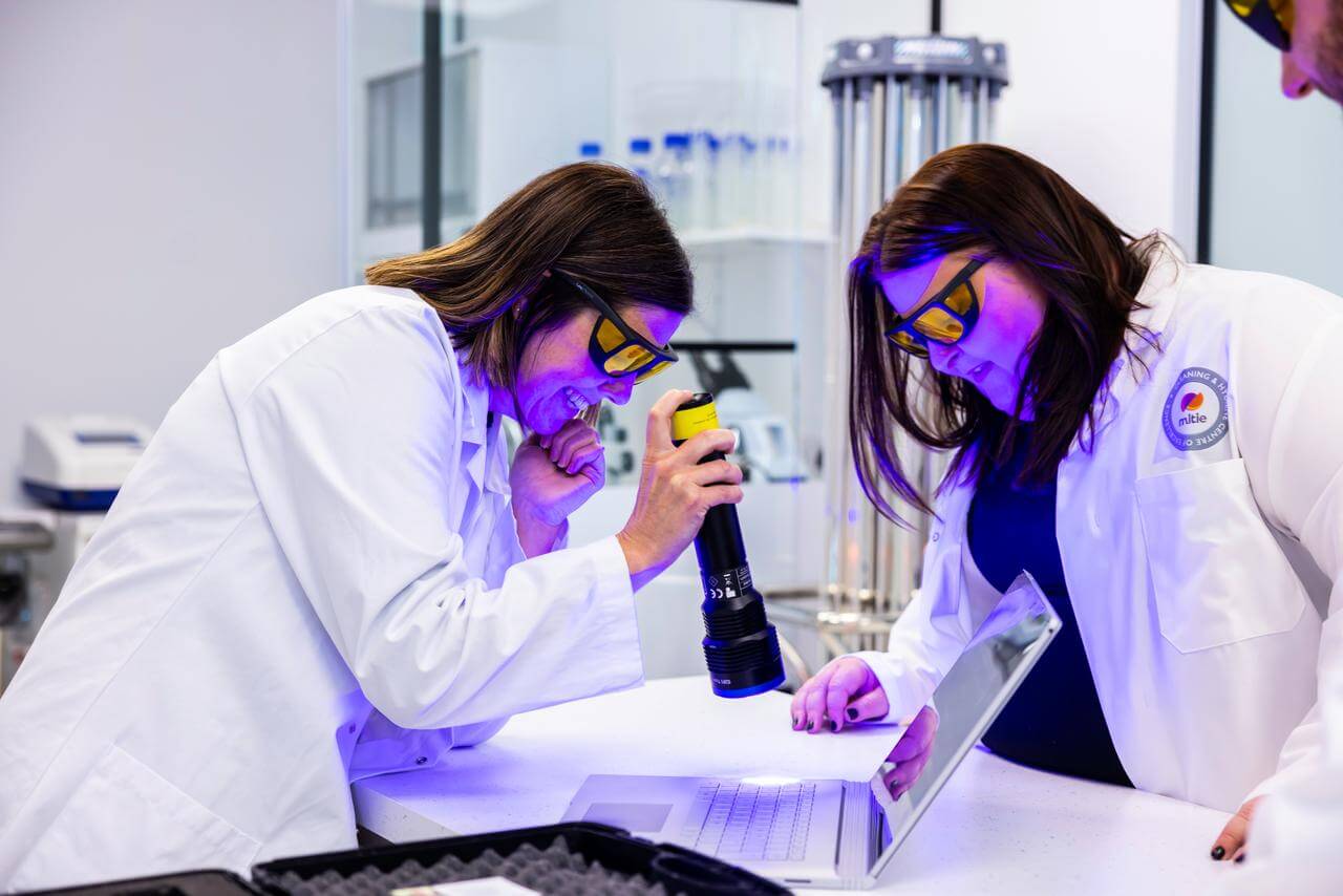 Mitie cleaning colleagues using a UV light on a laptop keyboard