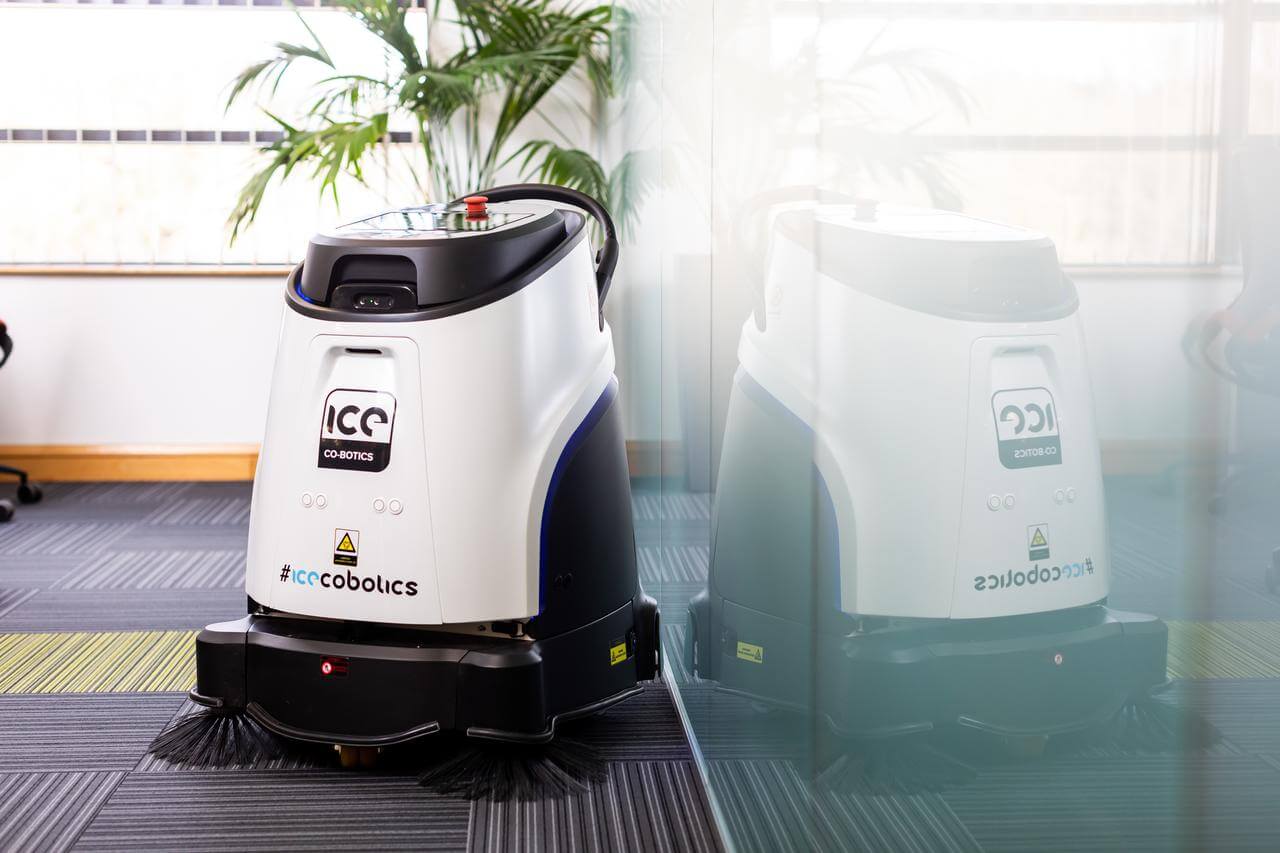 A white and black robotic vacuum cleaner in an office setting