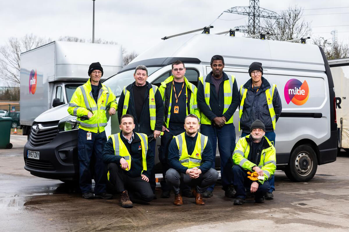 Team of Mitie workers in high-vis standing in front of a company van