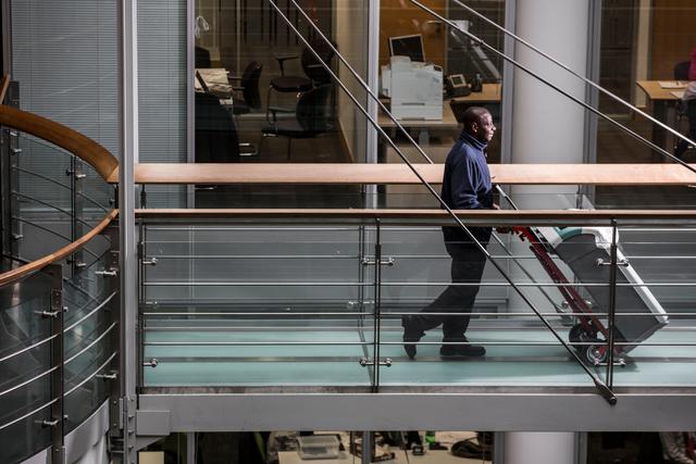 Mitie cleaner removing a waste bin in a corridor