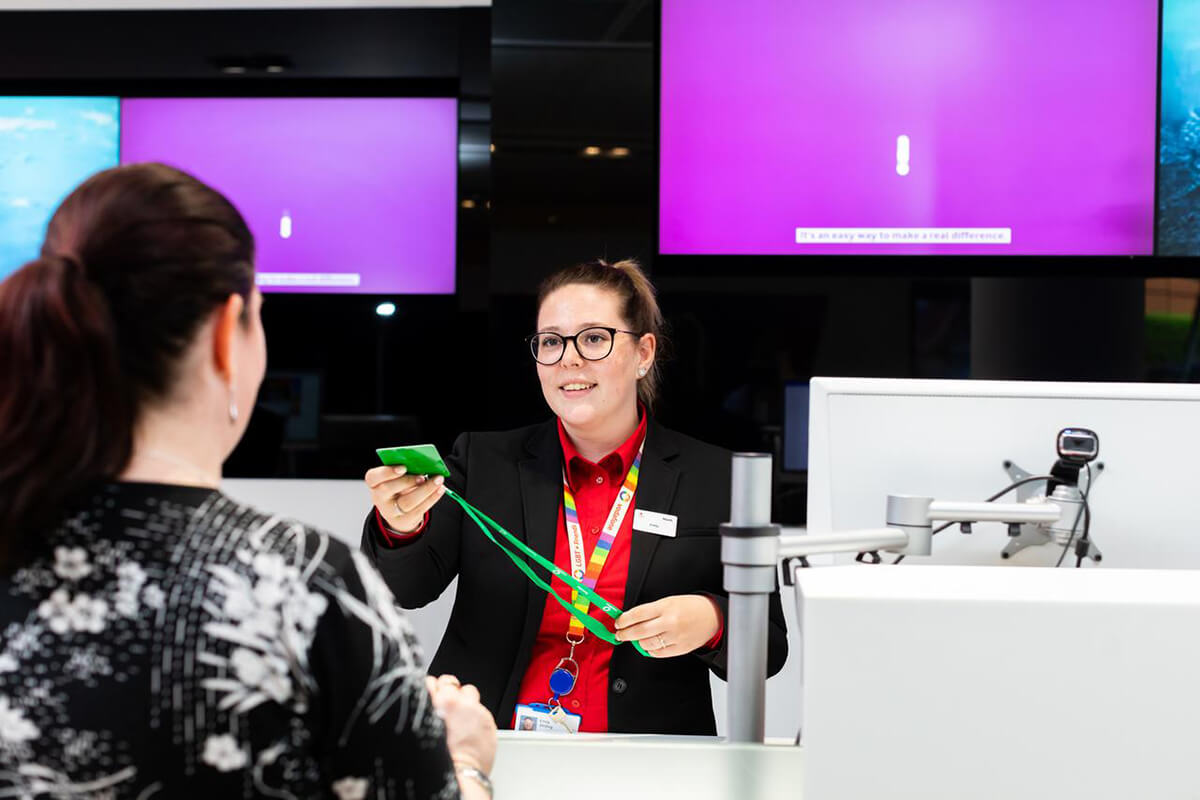 Female reception staff handing a guest pass to a visitor