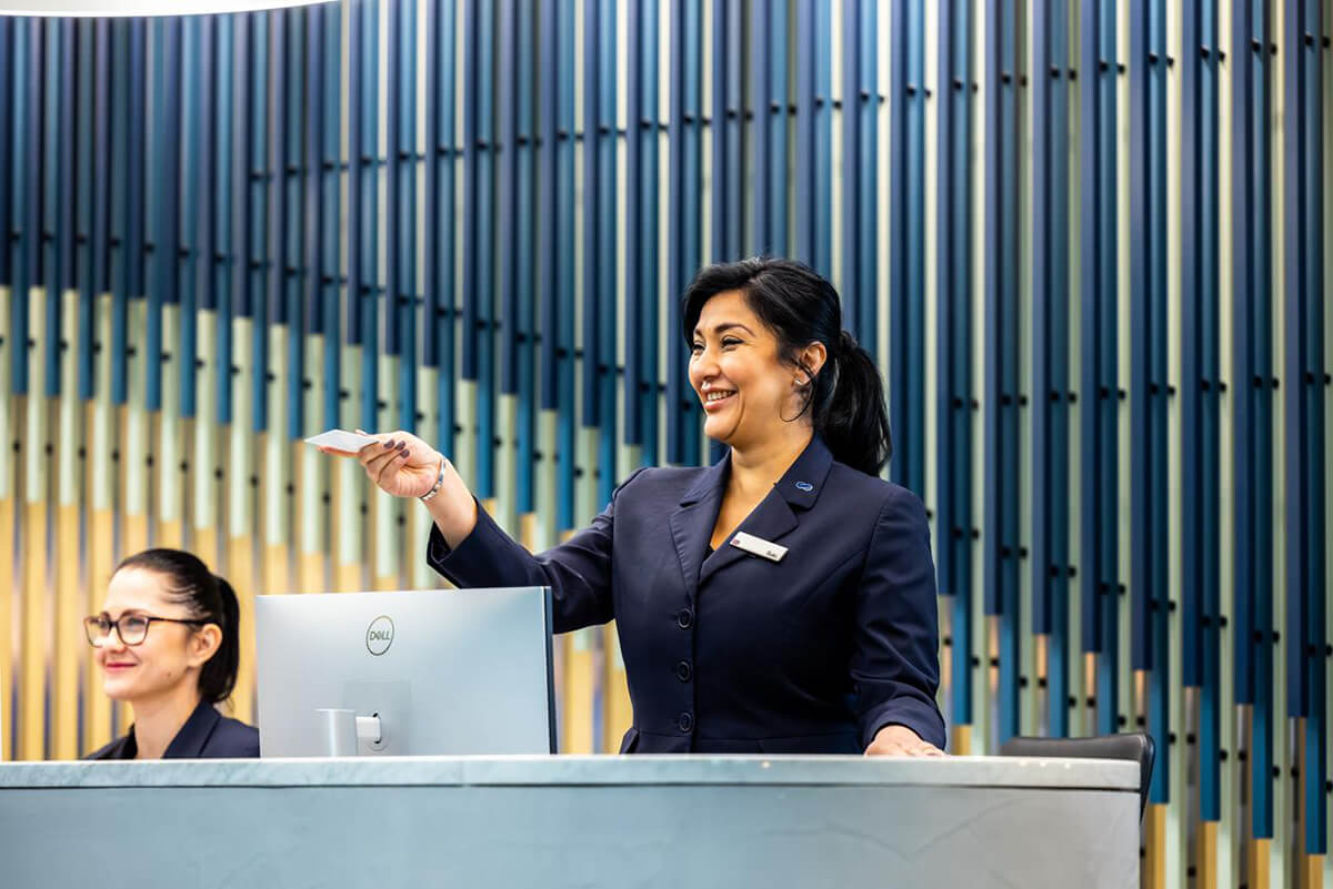 Female front of house reception staff handing an access card to a visitor
