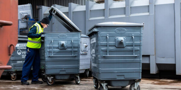 Mitie waste employee wearing high vis looking in a commercial waste bin