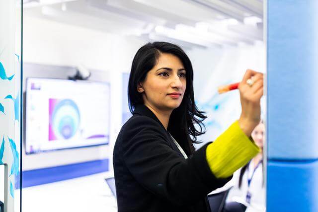 Professional woman writing on a whiteboard in an office