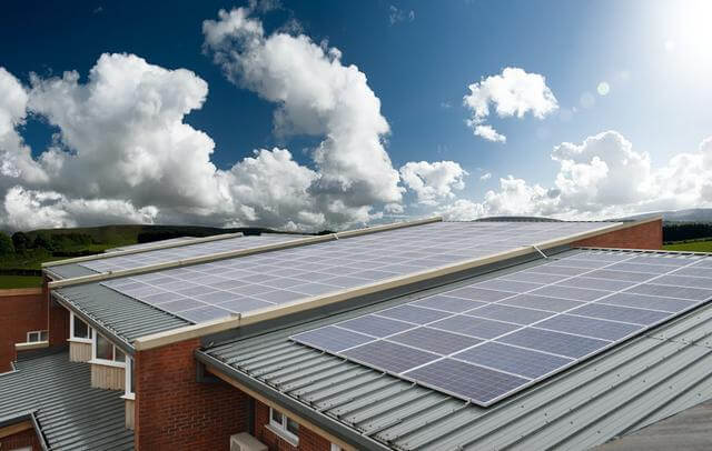 Solar panels on school roofs, with blue sky and clouds above