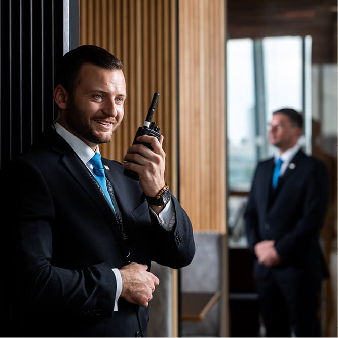 Two male suited security guards using mobile radios