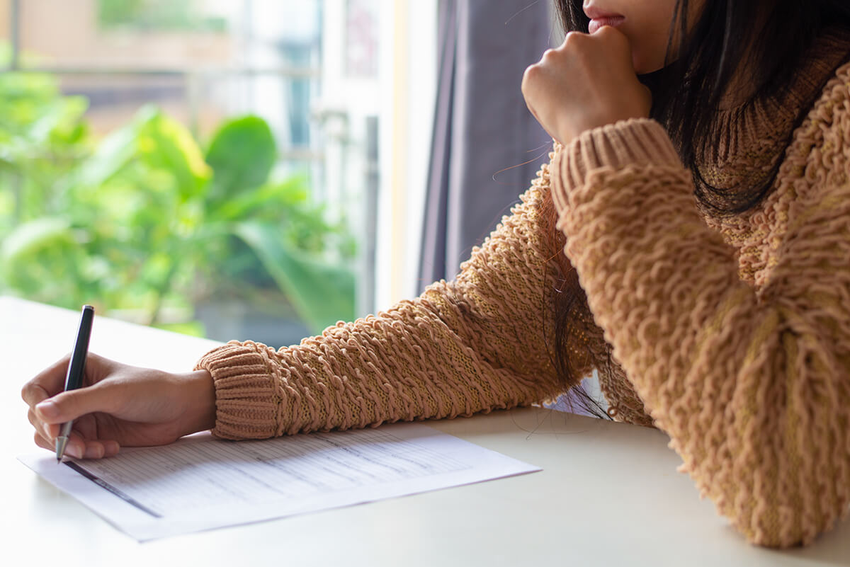 Close up of a women filling in a paper form with a pen