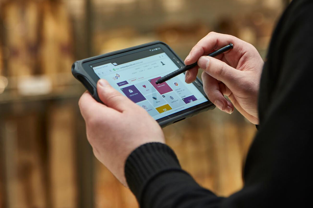 Male security guard in Sainsbury's using Mitie's Merlin security technology system with a stylus