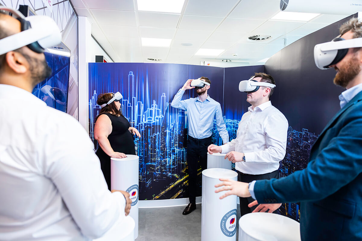 A group of people wearing white virtual reality (VR) headsets in the Mitie Cleaning and Hygiene Centre of Excellence, to experience virtual cleaning environments and training