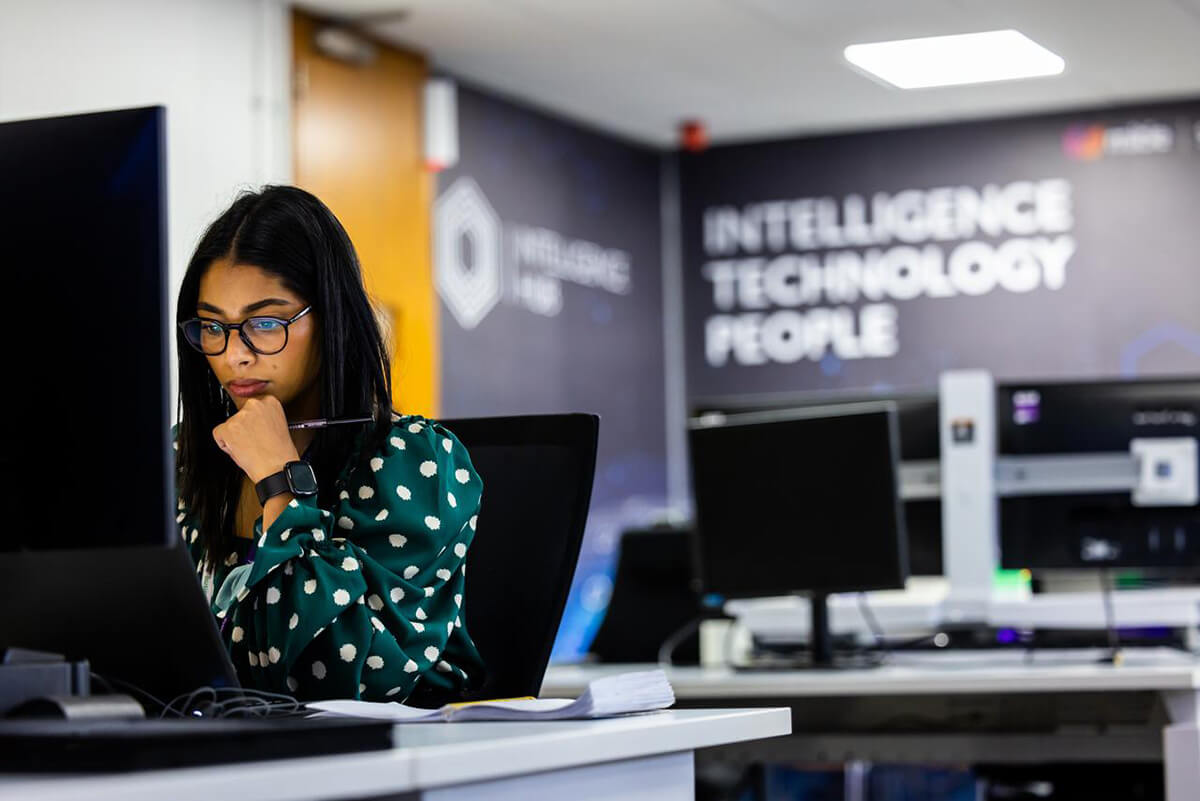 Woman in glasses working at a computer in the Mitie Intelligence Hub