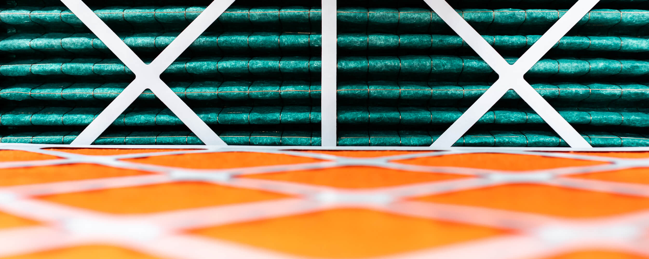 Close-up photography of rolls of orange and green insulating material being held in place with white cross frames