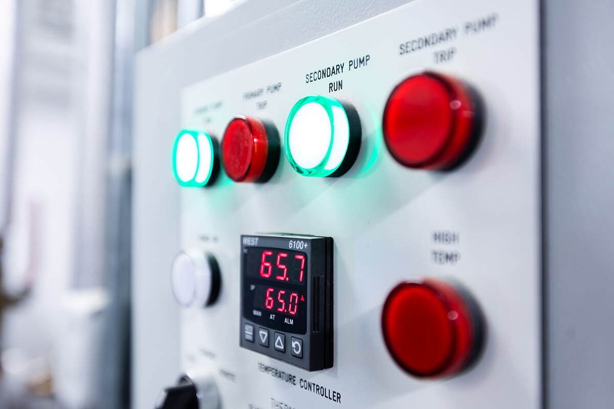 A close-up of red and green buttons on a control panel for pump machinery