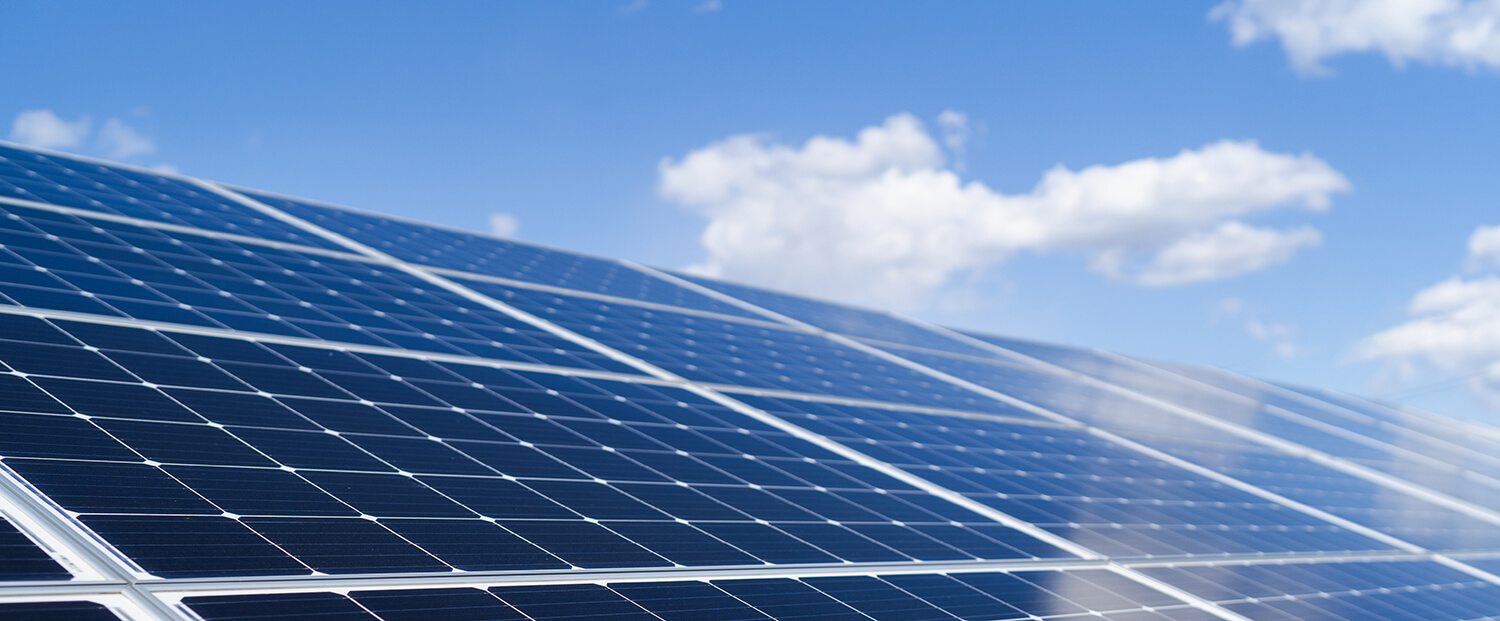 Angled solar panels against a blue sky with clouds