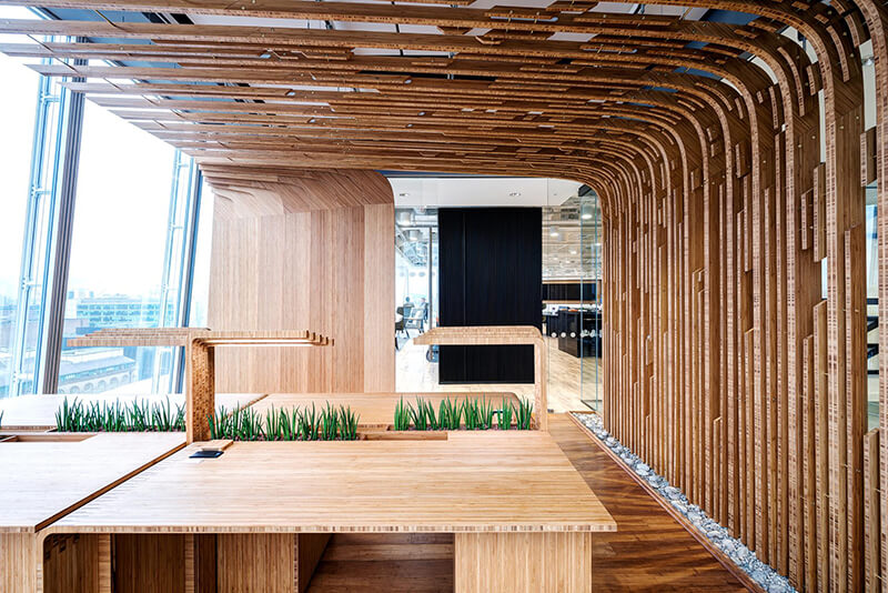 A meeting room at Mitie's offices in the Shard, London. The walls, desks and ceiling are all light patterned wood, with glass windows on the left