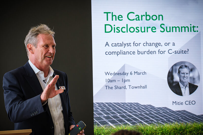 Phil Bentley, Mitie CEO, introducing the Carbon Disclosure Summit, dressed in a white shirt and dark suit