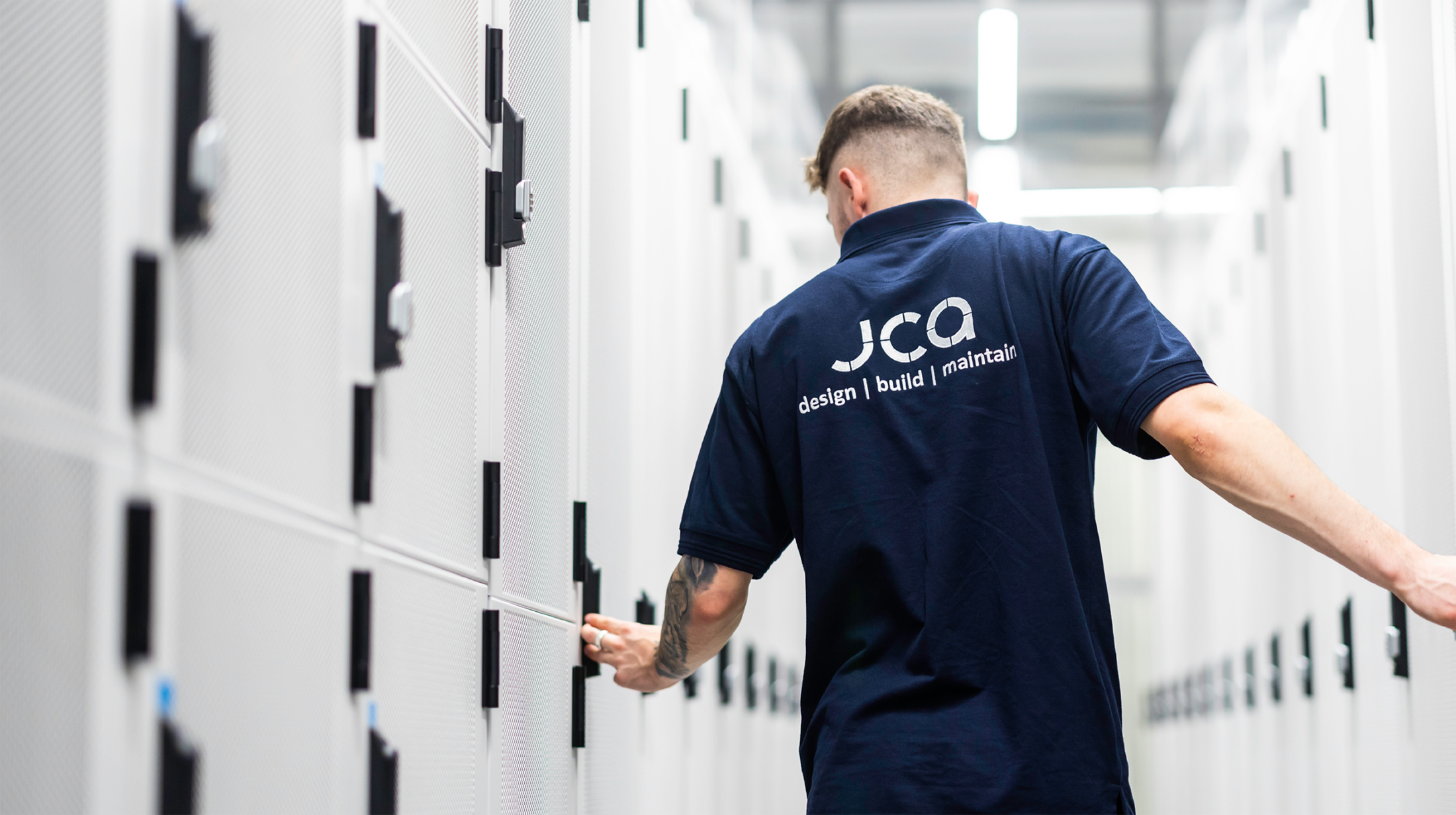 A male employee in a JCA branded dark blue polo shirt