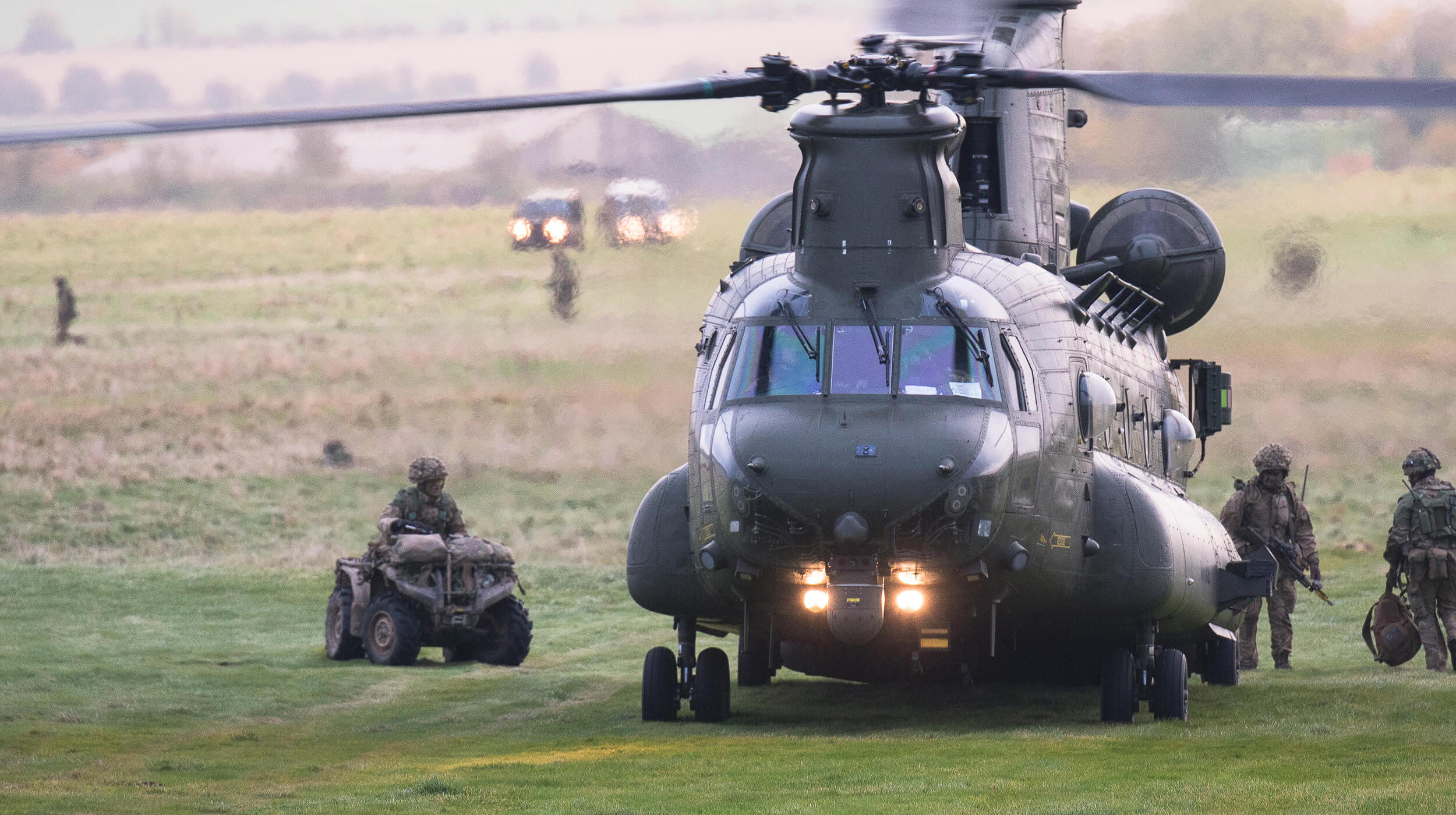 Royal Air Force Chinook helicopter on a field, with members of armed forces nearby