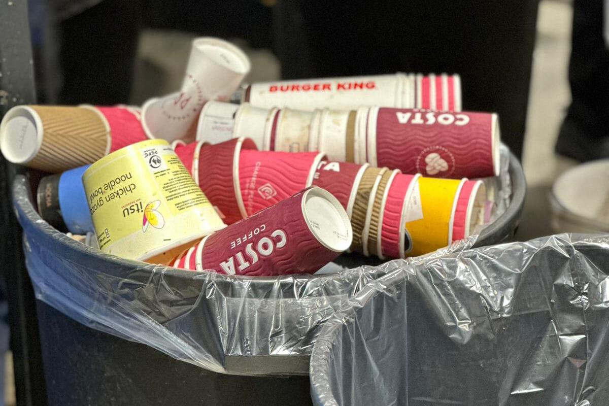 A waste bin filled with disposable coffee cups
