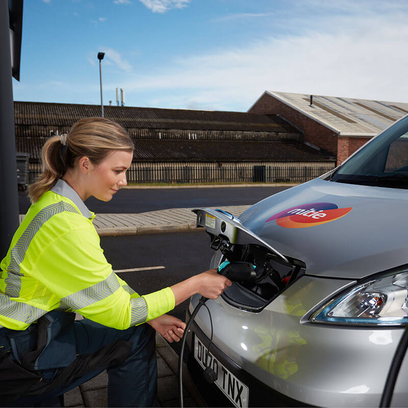 A Mitie employee in high vis plugging in a electric van to charge