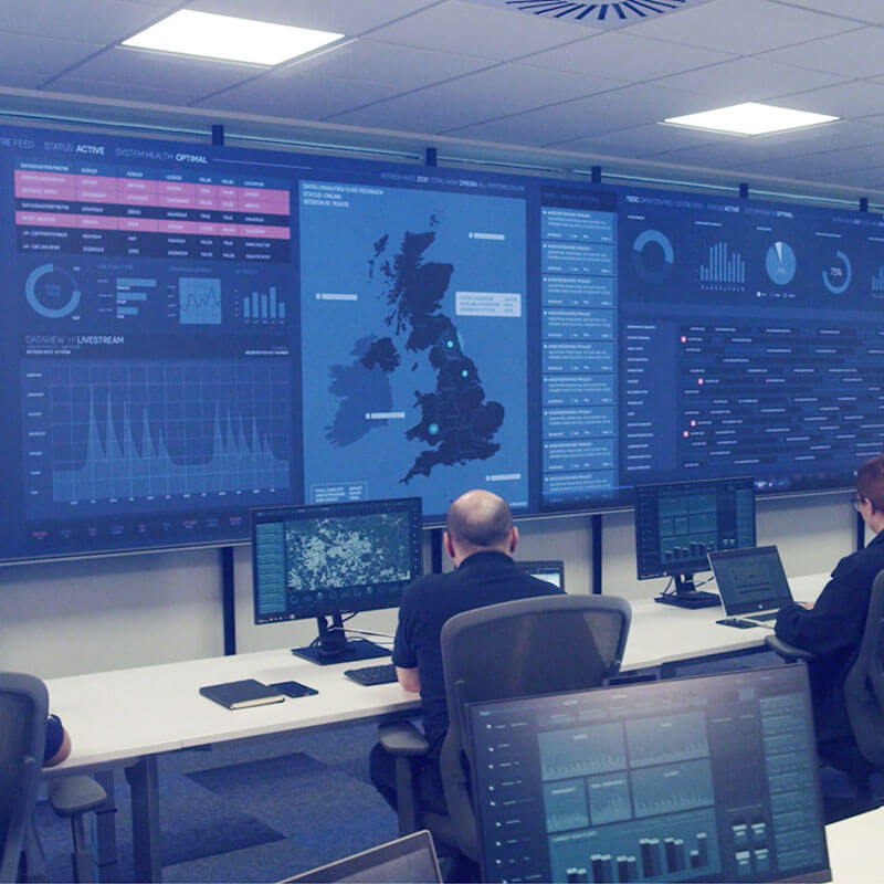 Mitie employees sitting in front of large screens showing various charts and data