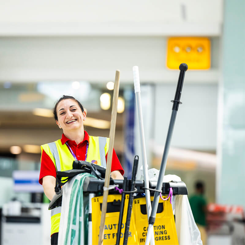 Mitie cleaner pushing a trolley of equipment and supplies