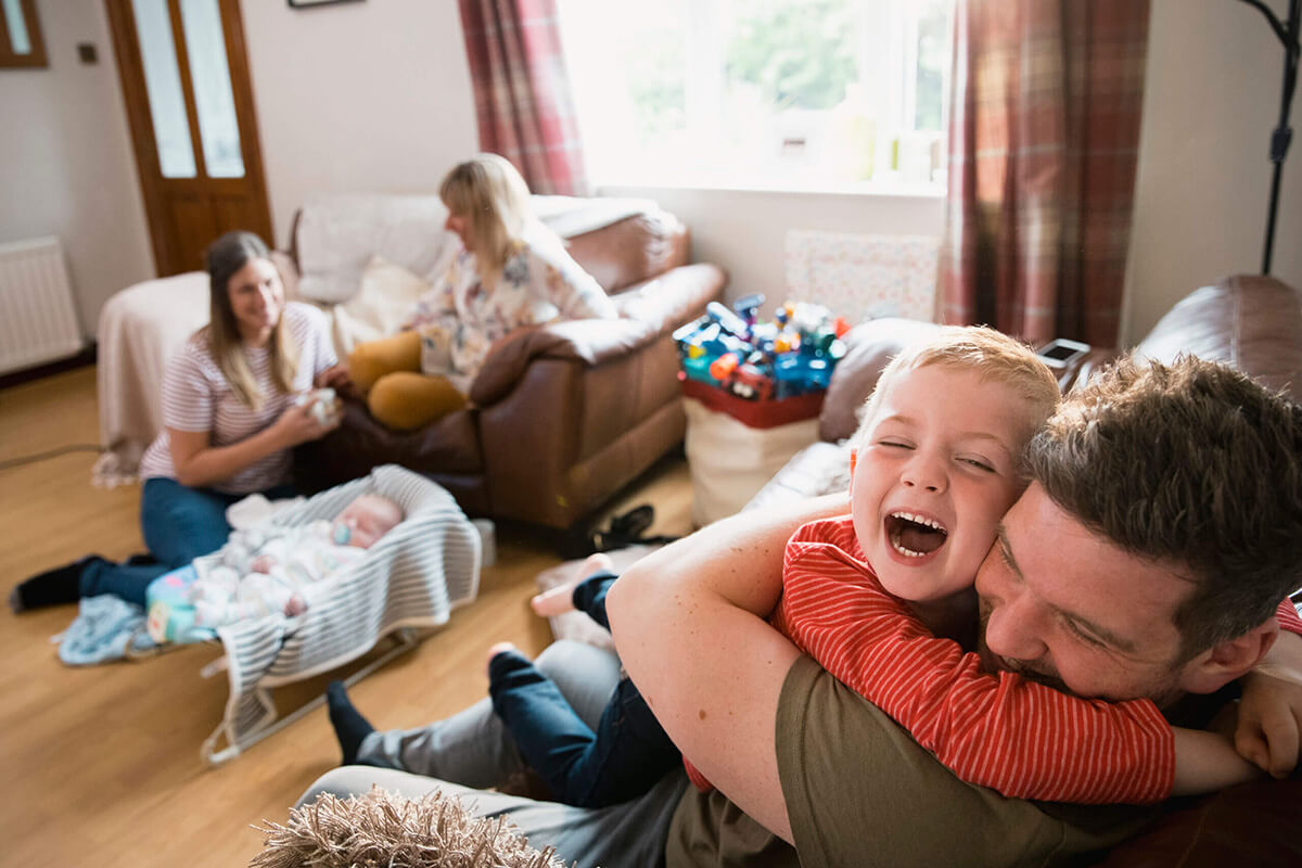 Family with two children and their grandmother sitting in the living room on sofa