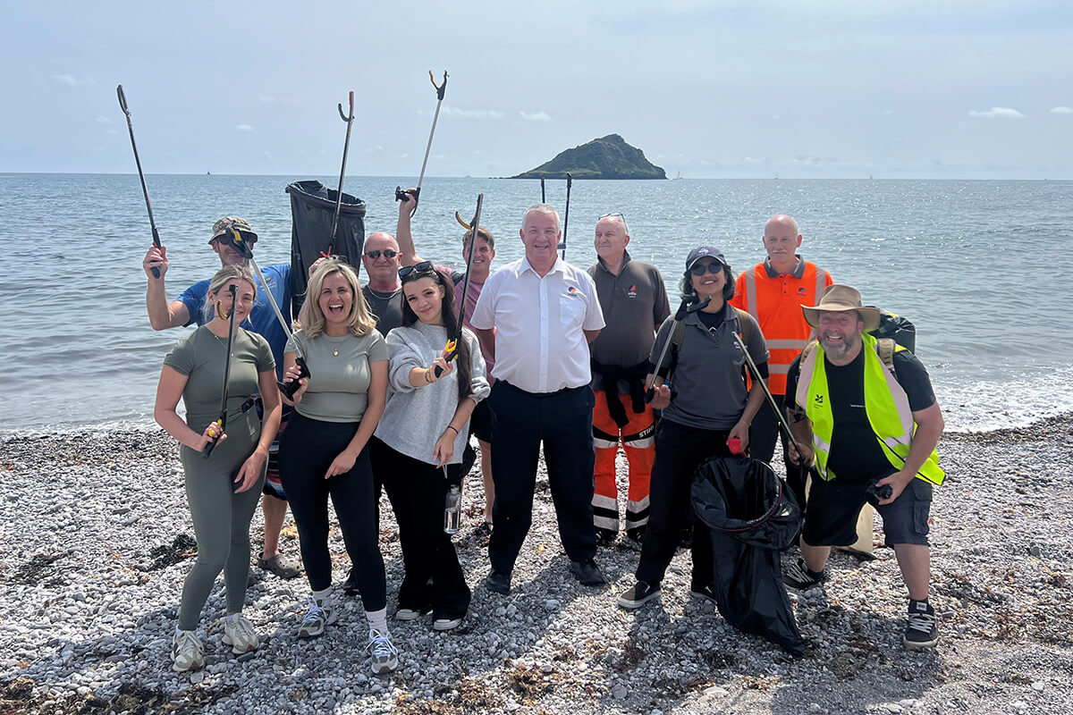 Mitie colleagues at HMS Drake standing on the beach with litter pickers
