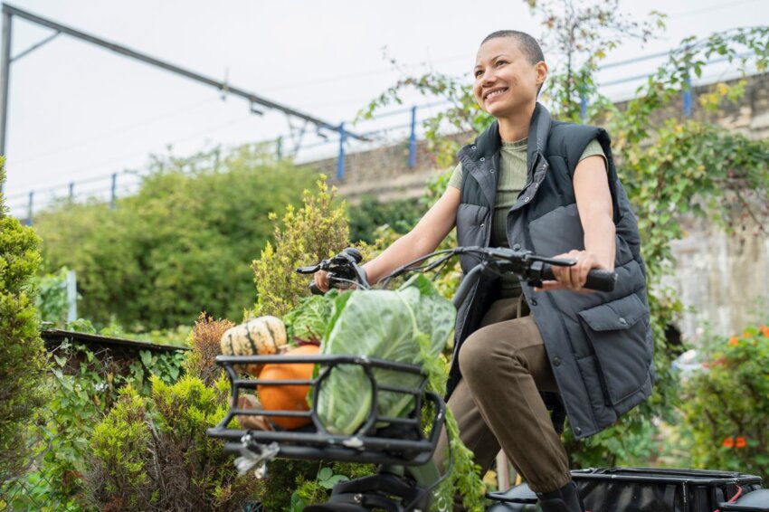 A woman riding a bicycle with vegetables in the basket
