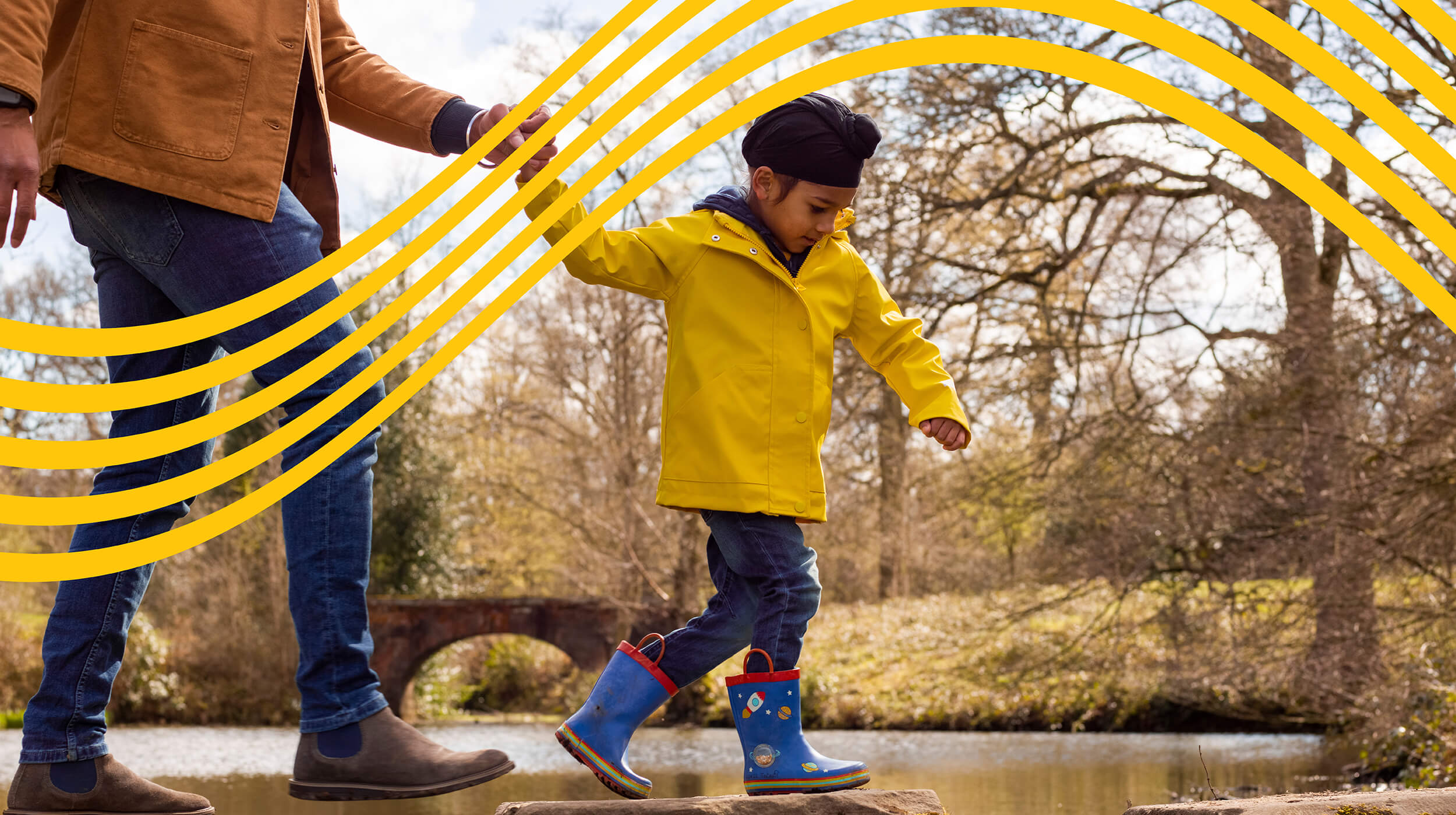 Young boy in a yellow raincoat crossing a river, with gold wavy lines in the background