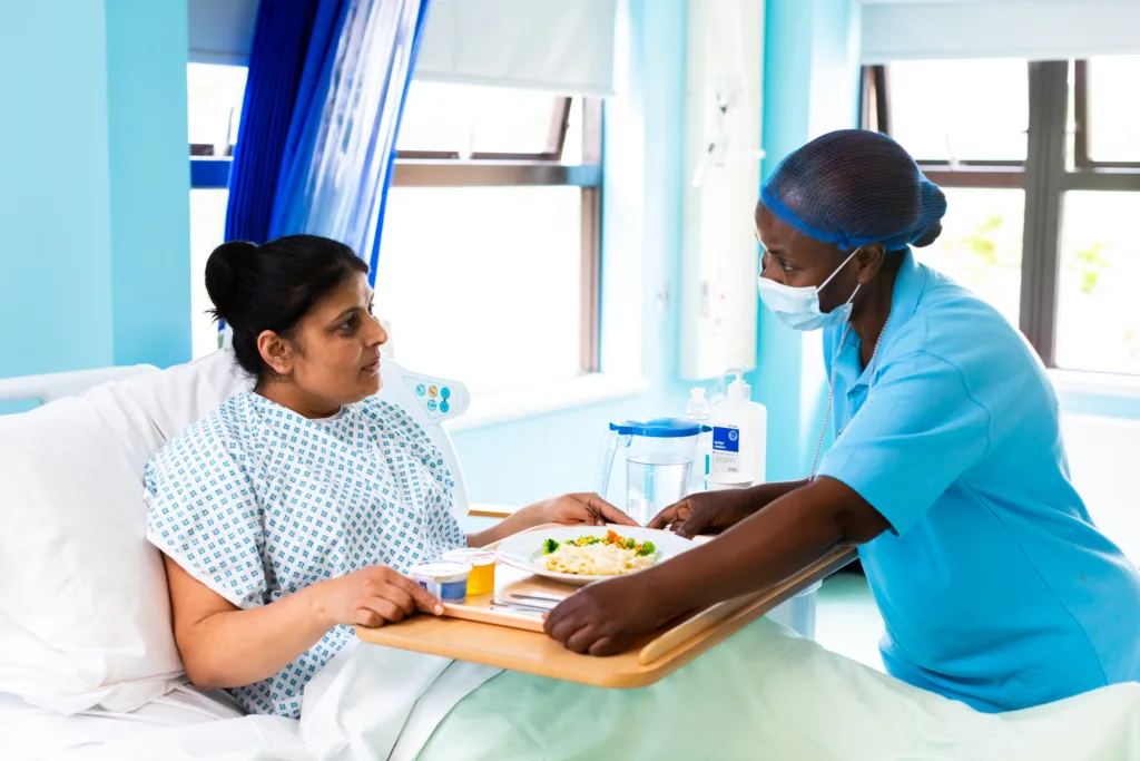 Patient in a hospital bed being served a meal