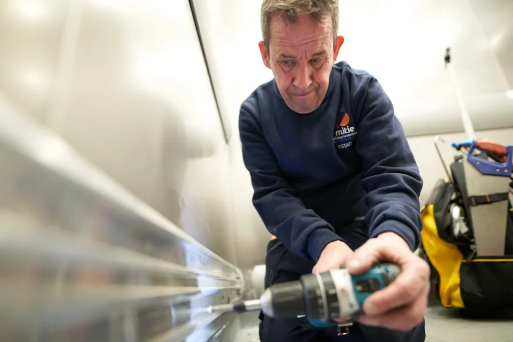 Mitie engineer with a drill