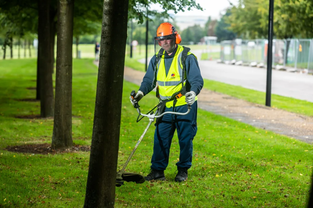 Mitie colleague strimming grass