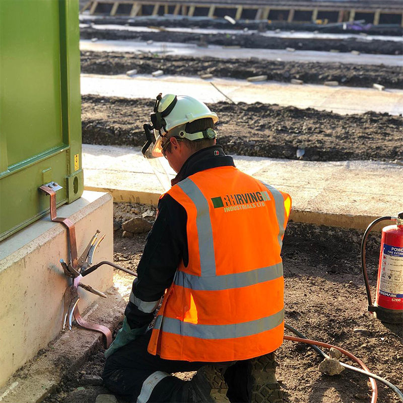 RHI Industrials engineer kneeling on the ground and installing equipment