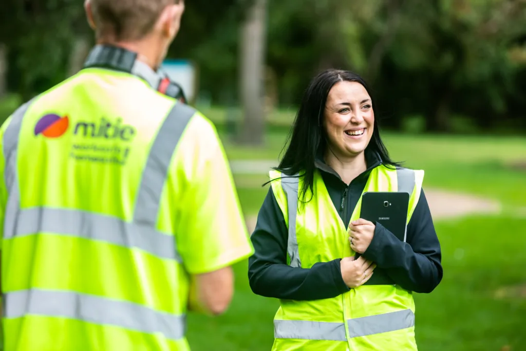 Two Mitie colleagues smiling and wearing high vis vests