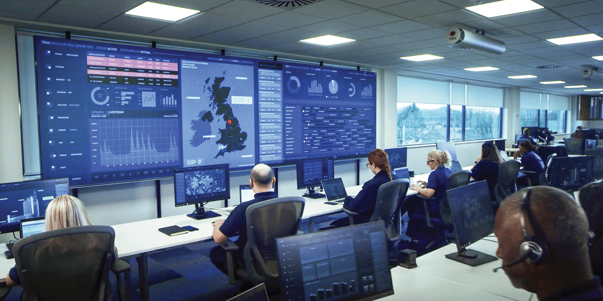 Colleagues working at computer screens in an operations control room.