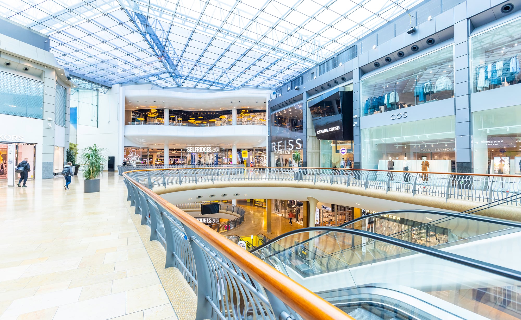 Interior of a modern shopping centre with shops, escalators and multiple levels.