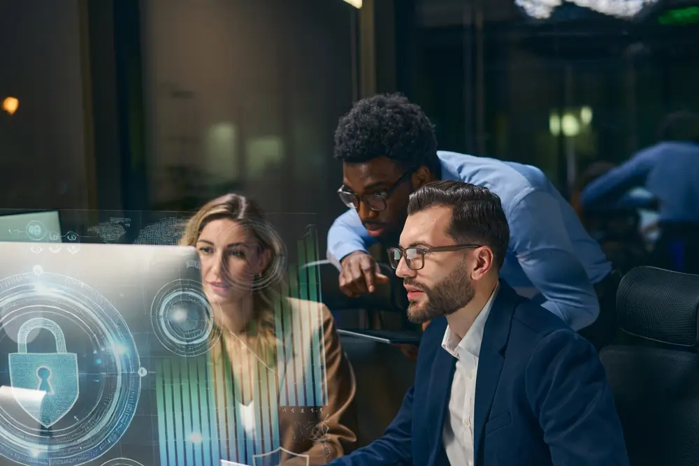 Three people reviewing data on a computer screen